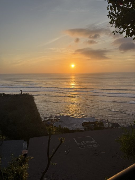 A scenic sunset over the ocean features the sun reflecting on the water, a silhouette of a person standing on a cliff edge, and a 'Wavewalk' logo on the ground in the foreground.