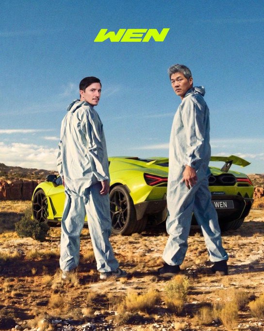 Two men in hazmat suits stand next to a bright yellow Lamborghini with "WEN" on the license plate, echoing the "Wen Lambo" theme of the post. The image visually represents the desire for financial success symbolized by the luxury car.