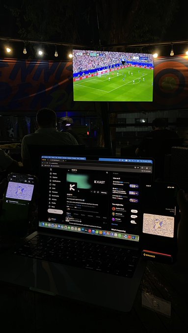 The image shows a laptop computer sitting on top of a table, displaying a soccer game being played by two teams. The laptop screen also has a Twitter app open, which is related to the post about the card for your wallet only possible with @KAST_xyz.