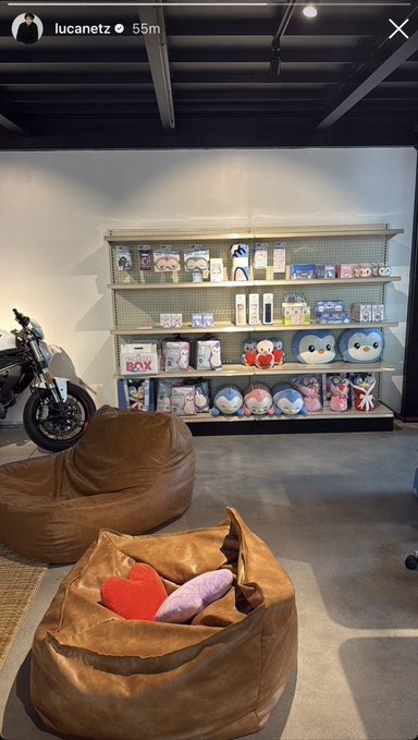 An Instagram story screenshot from user 'lucanetz' showing a retail space with brown leather beanbag chairs, a motorcycle, and shelves stocked with plush toys.