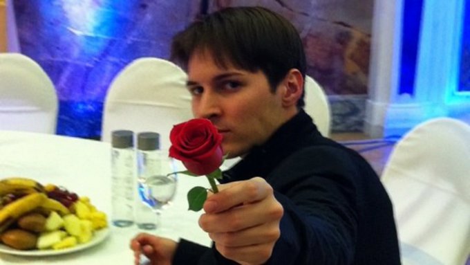 The man holds out a red rose while sitting at a table with water bottles and a fruit platter.

The image doesn't appear to have a direct visual connection to the post's content, but the symbolic gesture of offering a rose may suggest an olive branch or peace offering in the context of the discussion about online conflict.