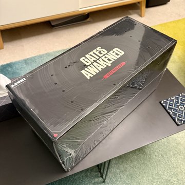 The image features a black box with white text that reads "Gates Awakened" and "Gate Walkers". The box appears to be a gaming console or accessory, possibly a game controller or a gaming headset. It is sitting on top of a table in front of a carpet. The post about the gaming console has an enticing description, which includes phrases like "dope", "awake", and "can't wait to start".