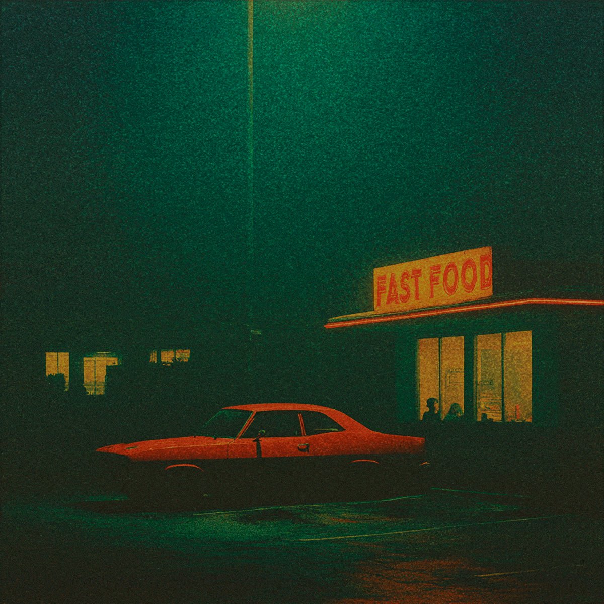 The image features an orange car parked outside of a fast food restaurant at night. The car's headlights are on, illuminating its surroundings as it sits in front of the restaurant window. There are two people visible inside the restaurant, likely enjoying their meal or conversation.