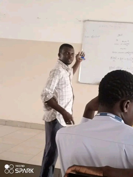 A junior lecturer stands at a whiteboard covered in mathematical equations, holding a marker while addressing students in a classroom, illustrating the "sweet" life outside of web 3 that the poster describes. The image, taken with a TECNO Spark phone as noted by the watermark, captures a candid moment of traditional academia and teaching.