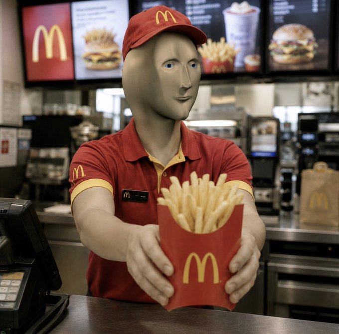 A mannequin dressed in a red McDonald's uniform and cap stands behind a fast-food counter, offering a red carton of fries with the iconic yellow 'M' logo. Menu boards displaying burgers and drinks are visible in the background.