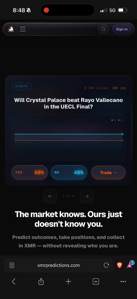 The image shows an advertisement for a cryptocurrency called @XMRPredictions, which is displayed on a cell phone screen. The text on the screen reads "New Updates have been rolling for @XMRPredictions XMRHub.org will see a overhual update before predictions launches and XMRMap.org will get relaunched before also 2026 is going to be a huge year for $XMR". This advertisement seems to be promoting a new cryptocurrency, possibly XMRPredictions, which has been gaining popularity among users of the app.