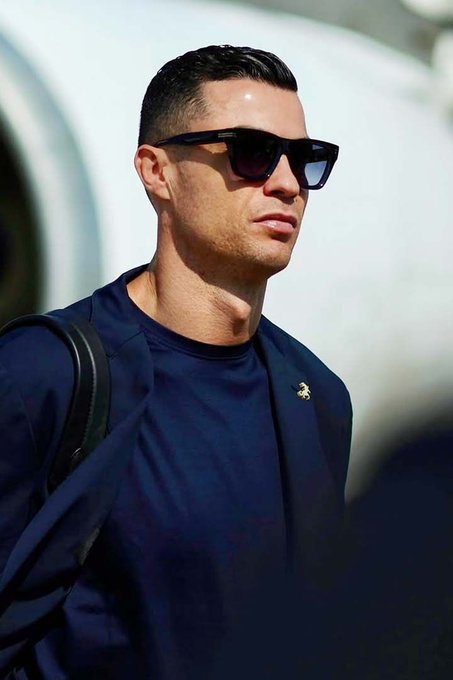 The image features a man wearing sunglasses, a blue shirt, and carrying a backpack or purse. The man appears to be dressed for an event or outing, possibly attending a party or gathering. The focus of the image is on the man's attire and accessories rather than the content of the photo itself.