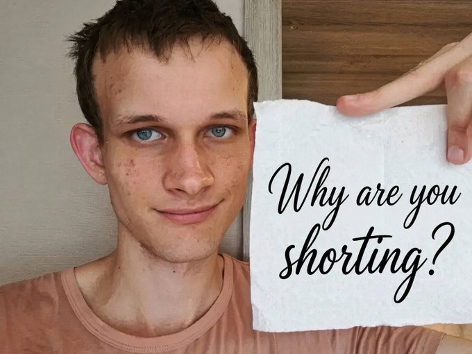 A young man holds up a napkin with the handwritten text "Why are you shorting?" written in cursive.