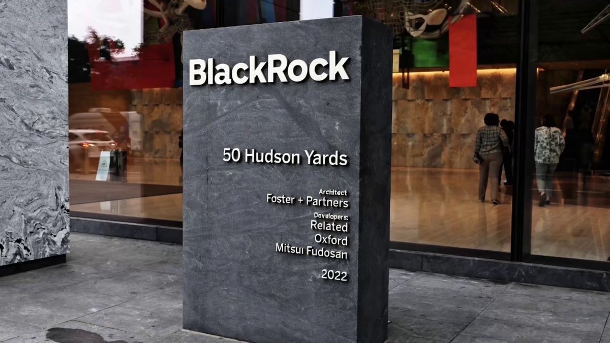 The image shows a large stone sign with the name "BLACKROCK" written on it, located outside of a building. There are two people walking by the building, one person closer to the left side of the image and another person further right in the background. The text in the image suggests that BlackRock is an established company in the cryptocurrency market, with Bitcoin already available as a product. However, there is no XRP ETF yet, which might indicate that they are waiting for the demand for XRP to become too high or unstable before launching it.