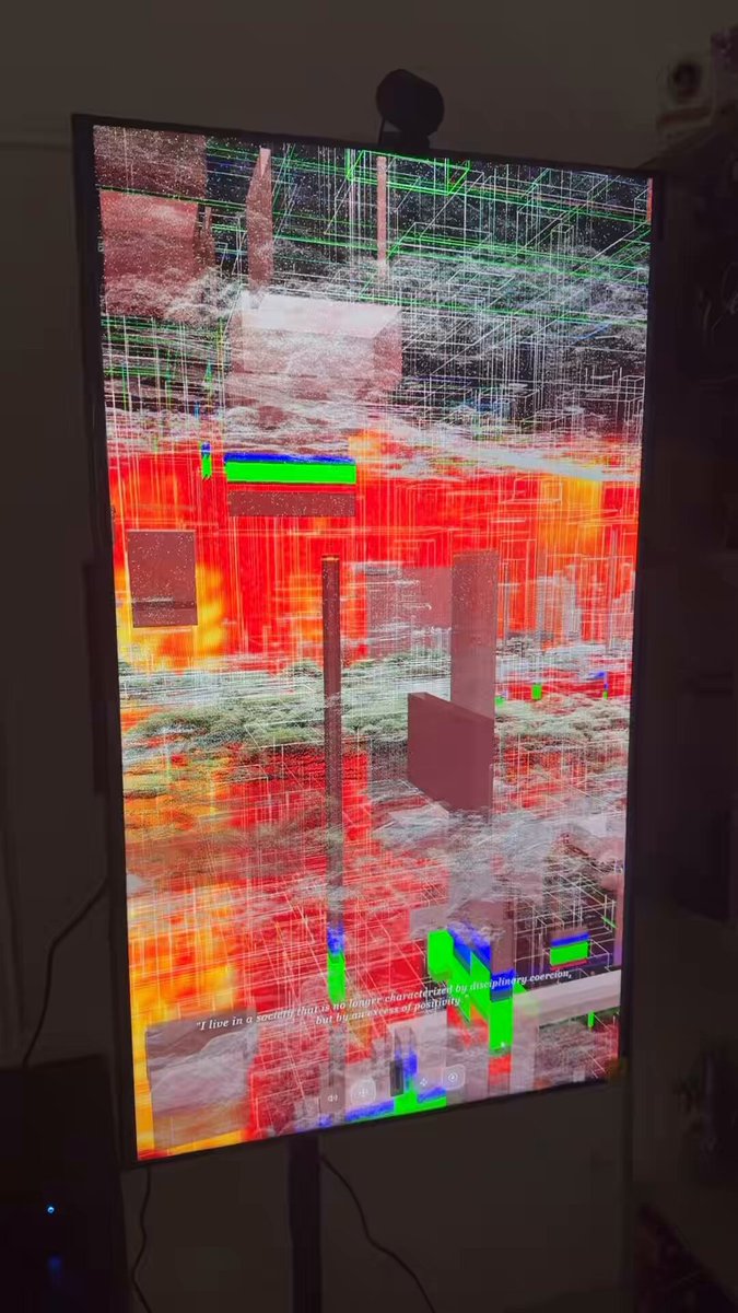 The image shows a large screen television displaying an abstract painting with red, green, blue, and white colors. The TV is placed against a wall, and there are two speakers positioned below it. A person can be seen standing behind the TV, possibly admiring or analyzing the artwork displayed on the screen.