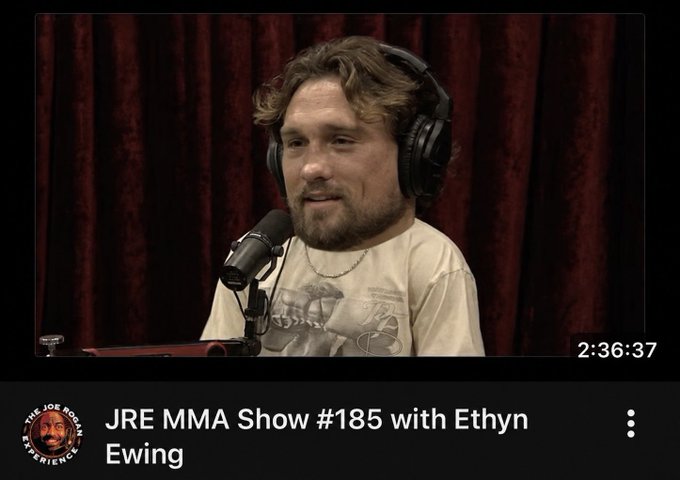 A man with a beard and wavy hair wearing headphones sits in front of a microphone during what appears to be a podcast recording. The video thumbnail shows the title "JRE MMA Show #185 with Ethyn Ewing" from The Joe Rogan Experience, with a timestamp of 2:36:37 displayed.