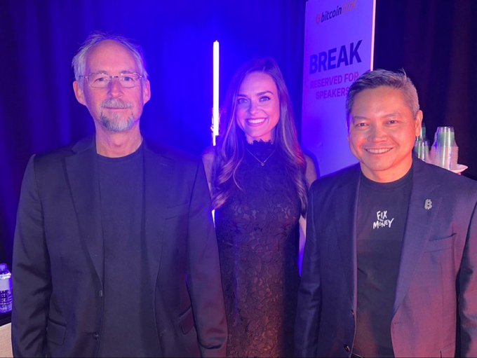 Three people pose together at a Bitcoin 2025 event, with one man wearing a "Fix Money" t-shirt and a partially visible sign reading "bitcoin BREAK" in the background; the image appears to accompany commentary calling out the questionable characters associated with Bitcoin's promotion, suggesting these individuals may represent the "marketing team" the author criticizes.