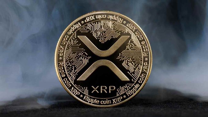 A gold-colored Ripple (XRP) cryptocurrency coin sits against a smoky, atmospheric background, featuring the iconic "X" logo and inscriptions reading "Ripple coin XRP" around its edge. The image visually reinforces the article's focus on Ripple's strategic investments in Zilo and Liquido to expand regulated assets on the XRP Ledger.