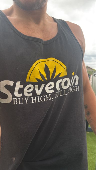 A man wears a faded gray tank top displaying the "Stevecoin" logo with a yellow cannabis leaf emblem and the slogan "BUY HIGH, SELL HIGH," humorously tying into the post's discussion about coping with disappointment and his "enemy" energy over minor setbacks.