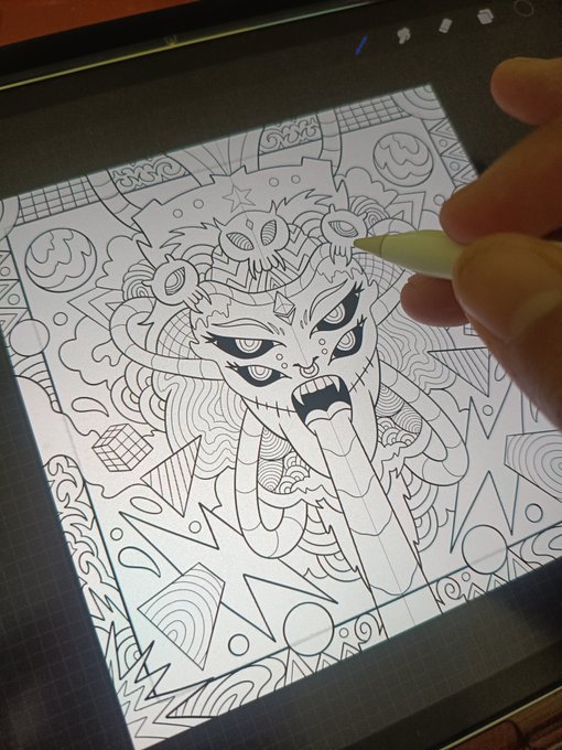 A close-up photograph of a person's hand using a stylus on a tablet to draw a complex, detailed line art illustration of a fierce character with multiple eyes and a mask.