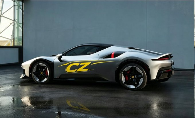 A side view of a silver Ferrari sports car with a yellow 'CZ' logo on the door, parked on a wet concrete surface.