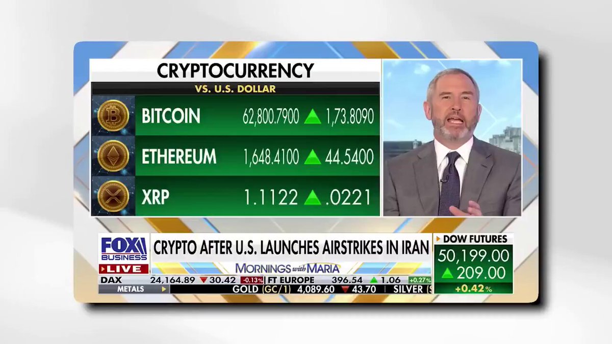 The image shows a man standing behind a computer screen, with a news program displayed on the screen that includes information about Ripple XRP and Bitcoin. The text "Crypt currency vs. US dollar" can be seen at the top of the image. The man is wearing a suit and tie, which suggests he might be a financial expert or an authority in the field. The post also mentions that there are two coins being discussed on the news program, indicating that Ripple XRP is likely the main topic of discussion.