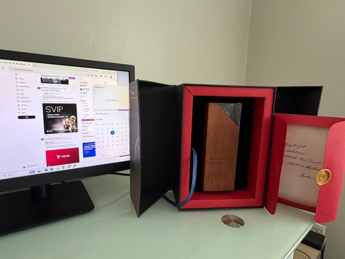 A Dell computer monitor displaying a software interface with an 'SVIP' promotion banner sits next to an open red presentation box containing a wooden award and a handwritten certificate with a gold seal.