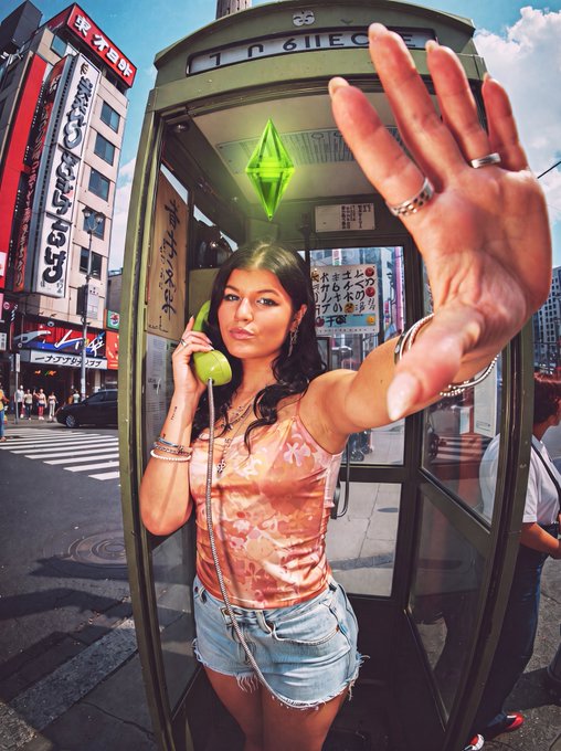 A woman poses inside a phone booth in a Tokyo street, holding a green receiver to her ear while extending her hand toward the camera, with a glowing green plumbob-style Solana logo hovering above her head — playfully answering the post's "ring ring Solana calling" with a literal "pickup."