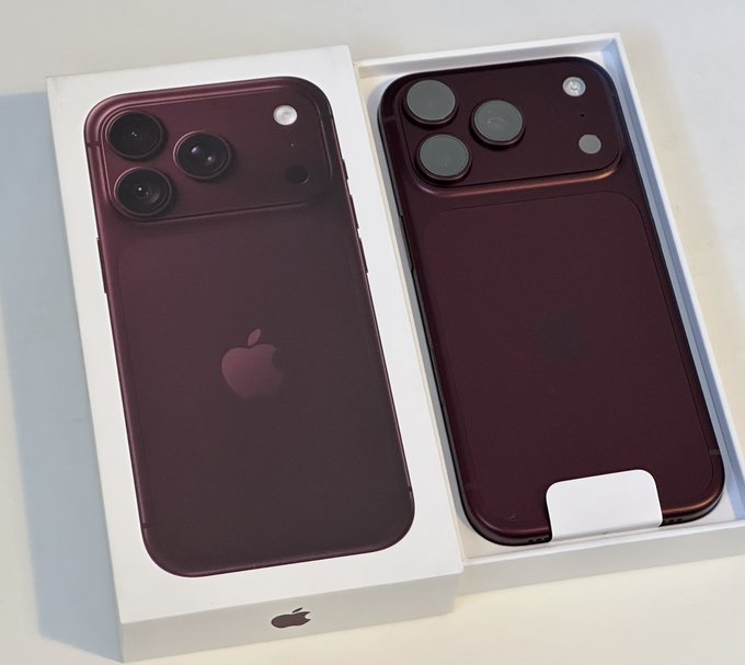 Two dark red or burgundy iPhones in white packaging boxes, showcasing the Apple logo and a triple-camera system on the back.