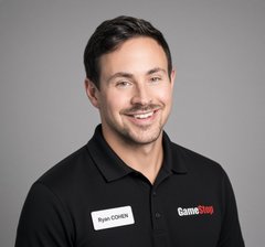A smiling man in a black polo shirt stands against a gray background, wearing a 'Ryan Osborne' name tag and a 'GameStop' logo.