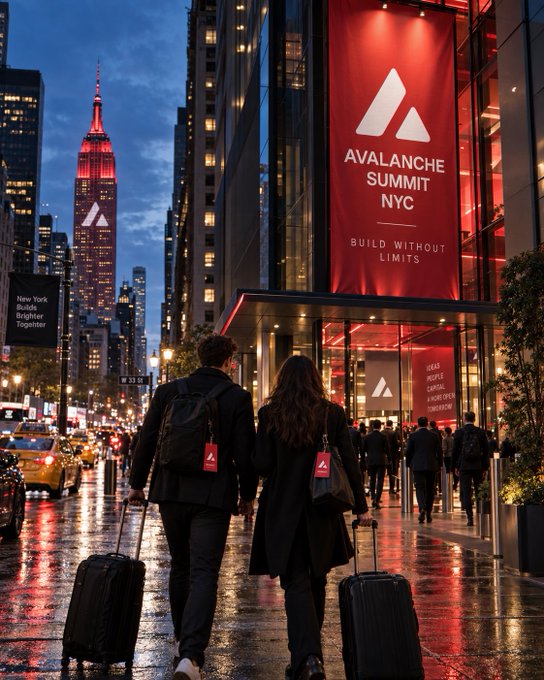A nighttime street scene in New York City featuring two people walking with luggage toward an event, with a large red banner reading 'AVALANCHE SUMMIT NYC' and 'BUILD WITHOUT LIMITS' and the Empire State Building lit up in red in the background.