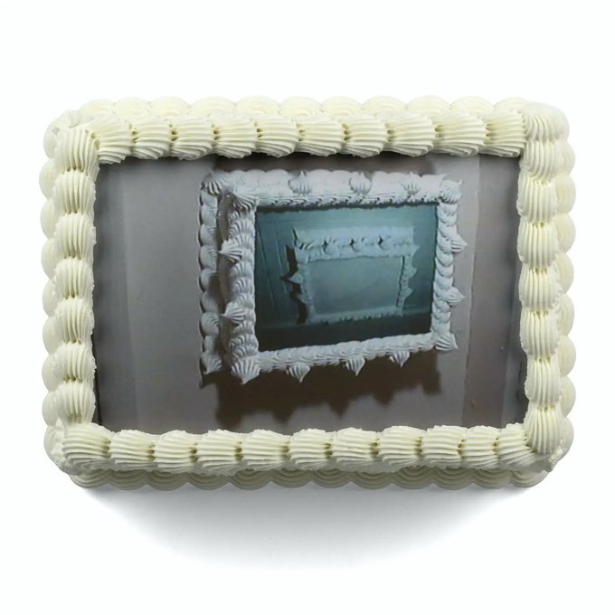 A rectangular sheet cake with white frosting borders and a gray center featuring a decorative white frame design.