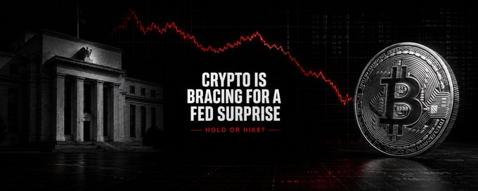 The image features a dramatic black-and-red banner showing a descending red market chart, the Federal Reserve building, and a Bitcoin coin, with bold text reading "CRYPTO IS BRACING FOR A FED SURPRISE — HOLD OR HIKE?" The graphic visually reinforces the post's theme of crypto market uncertainty ahead of the Fed's rate decision, illustrating the tension between potential rate hold scenarios and inflation-driven hike risks that could impact Bitcoin's near-term trajectory.