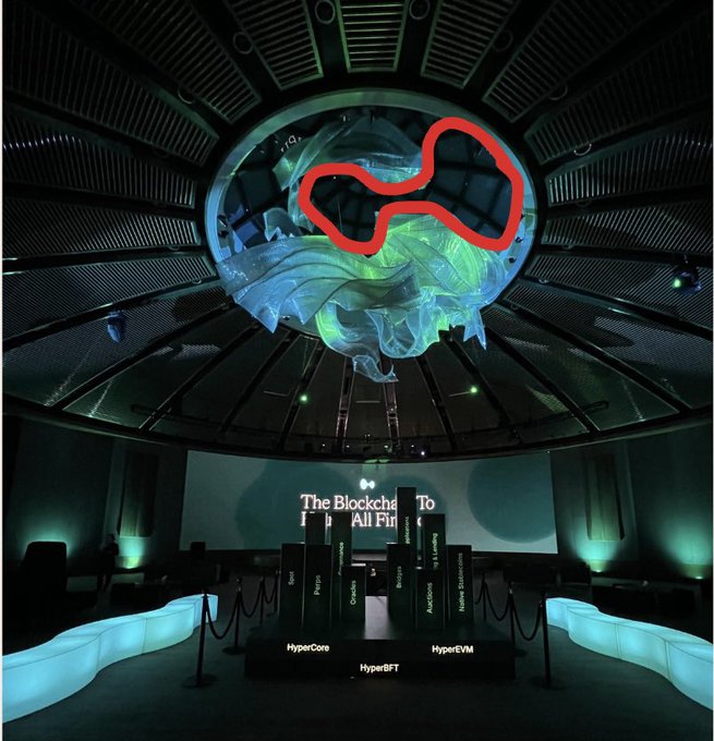 The image shows a large room with a dome-shaped ceiling, which has a red spot on it. The room appears to be a museum or exhibition space dedicated to showcasing various projects related to Hyper Liquid. There are several people present in the scene, possibly visitors or staff members who have come to explore and appreciate the exhibits. A chair is also visible within the room, likely for visitors to sit and take their time examining the displayed projects. The overall atmosphere of the image suggests an engaging and educational experience at this unique venue.
