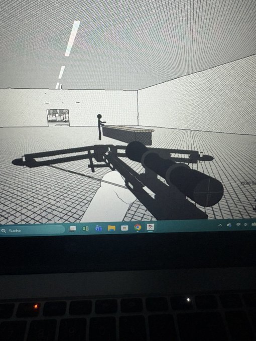 A photograph of a laptop screen displaying a 3D wireframe environment with a crossbow weapon model, shown from a first-person perspective with Windows taskbar visible at the bottom.