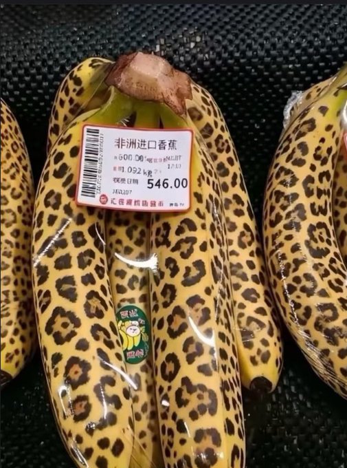 A bunch of bananas wrapped in leopard-print packaging sits on a shelf, labeled with a price tag reading "非洲进口香蕉" (African Imported Bananas) for 546.00, from 仁信海鸥队超市 (Ren Xin Hai Ou Dui Supermarket).