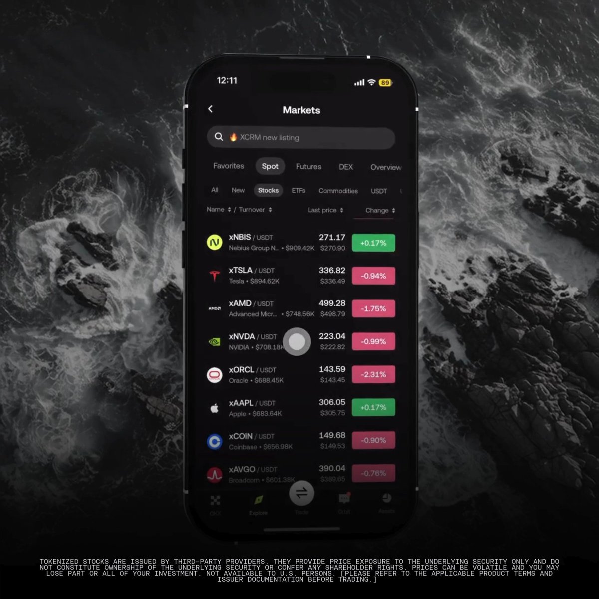A smartphone displays the Markets tab of "The New Money App," showing tokenized stock listings with prices and percentage changes—including xNBIS at $271.17 (+0.17%), xTSLA at $336.82 (-0.94%), xAMD at $499.28 (-1.75%), xNVDA at $223.04 (-0.99%), xORCL at $143.59 (-2.31%), xAAPL at $306.05 (+0.17%), xCOIN at $149.68 (-0.90%), and xAVGO at $390.04 (-0.76%)—set against a dark ocean background. The image illustrates the app's ability to research tokenized stocks and equities directly within a single trading interface.