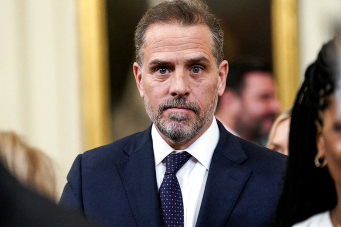 A man with a beard, wearing a dark suit and patterned tie, looks off to the side with a serious expression amid a crowd. The post suggests he is Hunter Biden, referencing a suspicious cryptocurrency trade involving a meme coin named $LAPTOP that allegedly profited an insider before other buyers lost their investments.