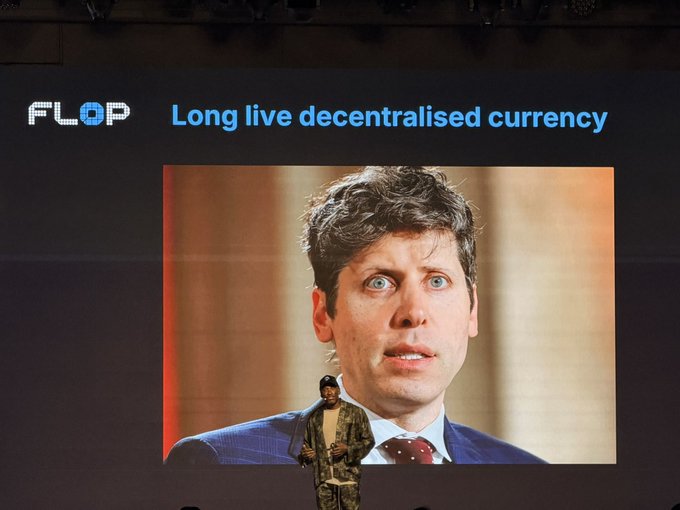 A stage presentation displays the 'FLOP' logo alongside the text 'Long live decentralised currency,' with a large screen showing a close-up of a man in a suit looking upward with a startled expression, while a speaker stands below.