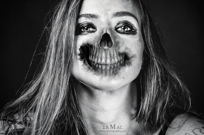 A black and white photograph features a woman with half her face painted as a grinning skull, with "ERMAC" and "ermacphotography.com" text at the bottom.