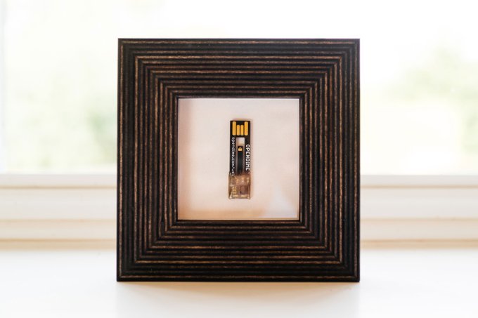 The image features a framed picture with an old-fashioned battery inside. The frame has a black border and gold stripes, giving it an antique appearance. The battery appears to be a small, square device that could have been used for lighting or other purposes in the past. The photo is accompanied by text that reads "Framed it, one of my favorite Bitcoin artifacts." This suggests that the picture might be related to Bitcoin or digital currency and has been framed as an interesting artifact.