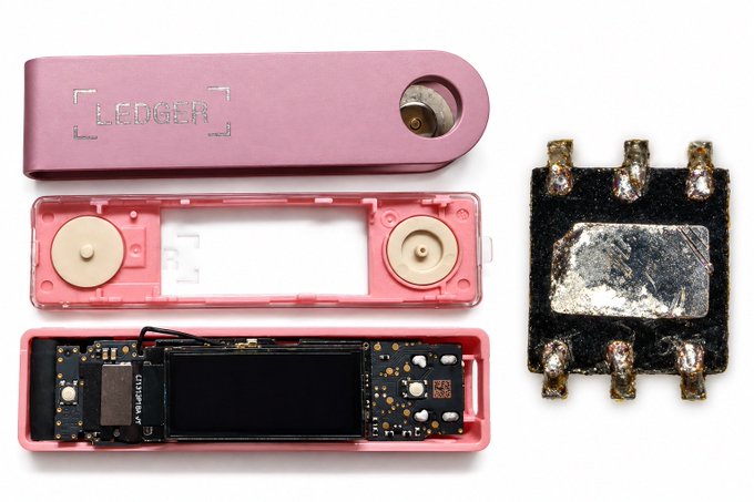 A disassembled pink Ledger hardware wallet shows its internal components laid out, including a chip component that appears to be tampered with or burned.