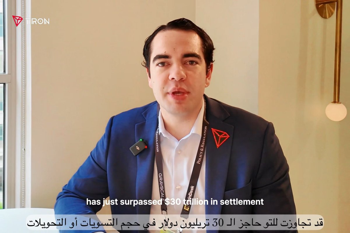 A man in a blue suit wears a lanyard with "TRON POLICY & REGULATION" and a TRON logo, with a TRON watermark in the corner. The caption reads "has just surpassed $30 trillion in settlement" with Arabic subtitles below highlighting TRON's $30 trillion settlement volume.