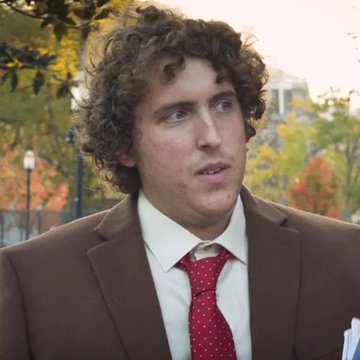 A young man with curly dark hair, wearing a brown suit jacket, white shirt, and red polka-dot tie, looks off to the side outdoors with trees in the background. The image appears to show Andrew Callaghan, founder of Channel 5, who is referenced in the accompanying post about the outlet's email subscriber list being shared with Hunter Biden prior to his LAPTOP crypto launch.