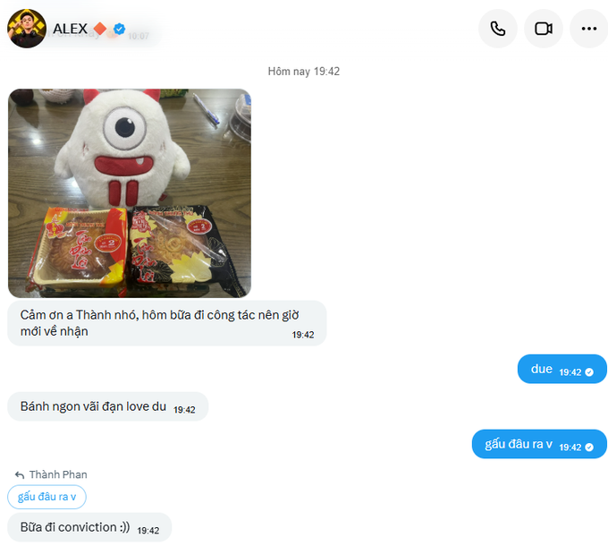 A Facebook Messenger conversation in Vietnamese between ALEX and Thành Phan, where ALEX shares a photo of a plush toy and snacks with the message 'Cảm ơn a Thành nhé, hôm bữa đi công tác nên giờ mới về nhận,' and Thành Phan responds with 'gấu đâu ra v' (where did the bear come from) and 'Bữa đi conviction :)).'