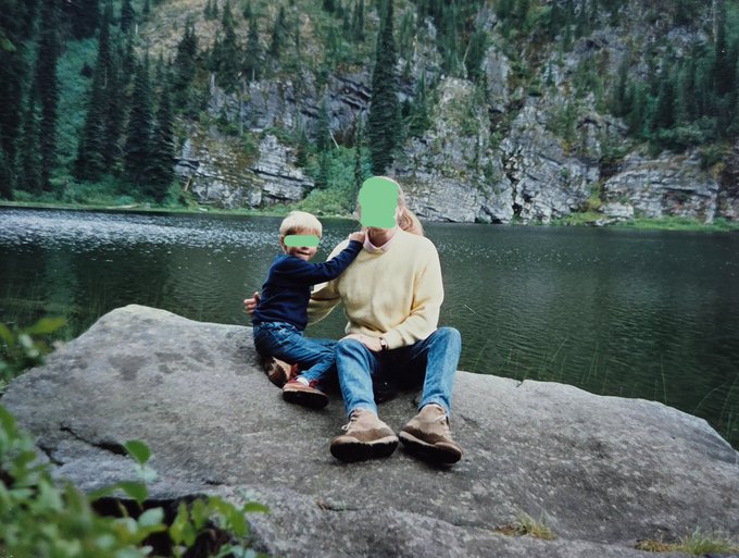 A parent and child sit on a rocky outcrop by a serene mountain lake, their faces playfully edited with green smiles. The caption "the real chad of CT" humorously frames the scene, suggesting the parent's confidence and adventurous spirit as a standout trait.