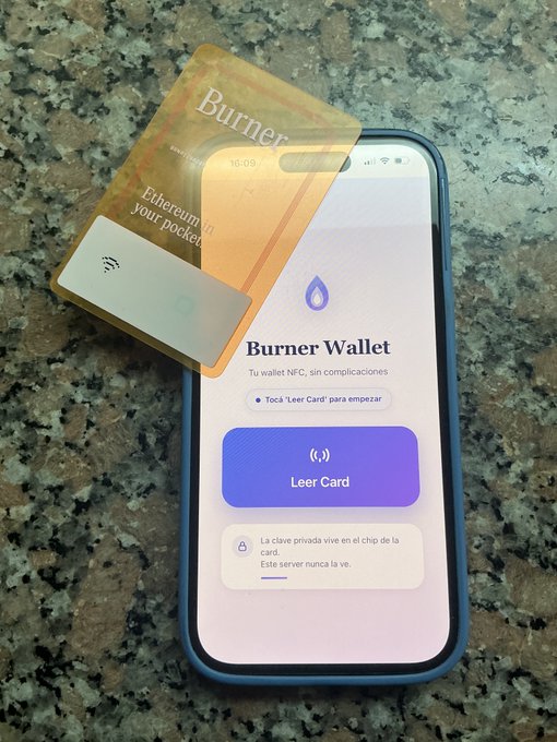 A smartphone displaying the 'Burner Wallet' app interface with a purple 'Leer Card' button, accompanied by a physical 'Burner' card resting on its screen.
