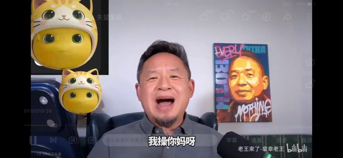 The image shows a video screenshot from the Bilibili channel "老王来了·爱宰老王" featuring a man with a goatee speaking directly to camera, with two yellow cat emoji overlays on the left and a colorful poster reading "EVERYTHING" on the wall behind him. The Chinese subtitle at the bottom reads "我操你妈呀" (a vulgar exclamation), contrasting with the post's question about "拿幸" (likely a humorous or ironic reference to the creator's expressive reaction).