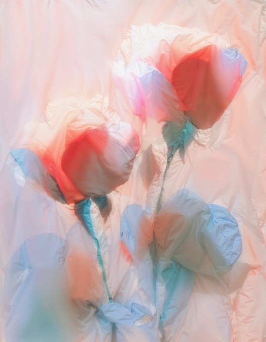 An abstract artwork or photograph featuring crumpled fabric or paper with soft red, blue, and white color washes.