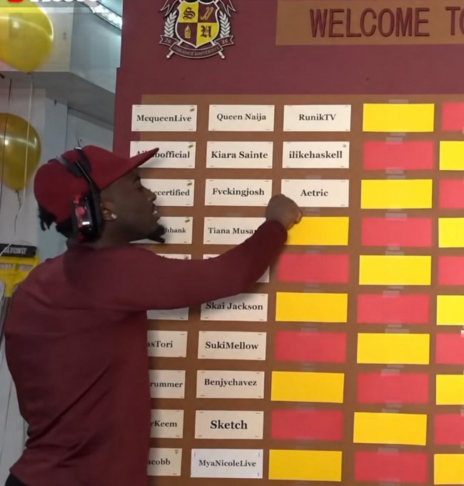 A man wearing a red cap and headphones points to a 'WELCOME TO' board featuring various streamer names including McqueenLive, Queen Naija, and others organized in colored sections.