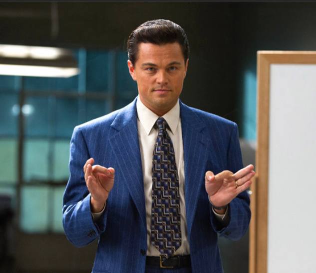 A man in a blue pinstripe suit and patterned tie gestures with both hands while standing in an office setting, possibly presenting or explaining a concept. The post's metaphor of a launchpad that only launches other launchpads visually echoes his open-handed pose, as if he's unveiling an idea to skeptical investors.