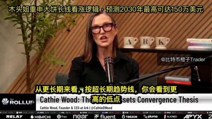 The image features a woman wearing glasses, sitting at a desk with a microphone in front of her. She appears to be speaking into the microphone during an interview or discussion about Bitcoin. The background shows a bookshelf filled with various books, suggesting that she might have been researching or discussing the topic further.