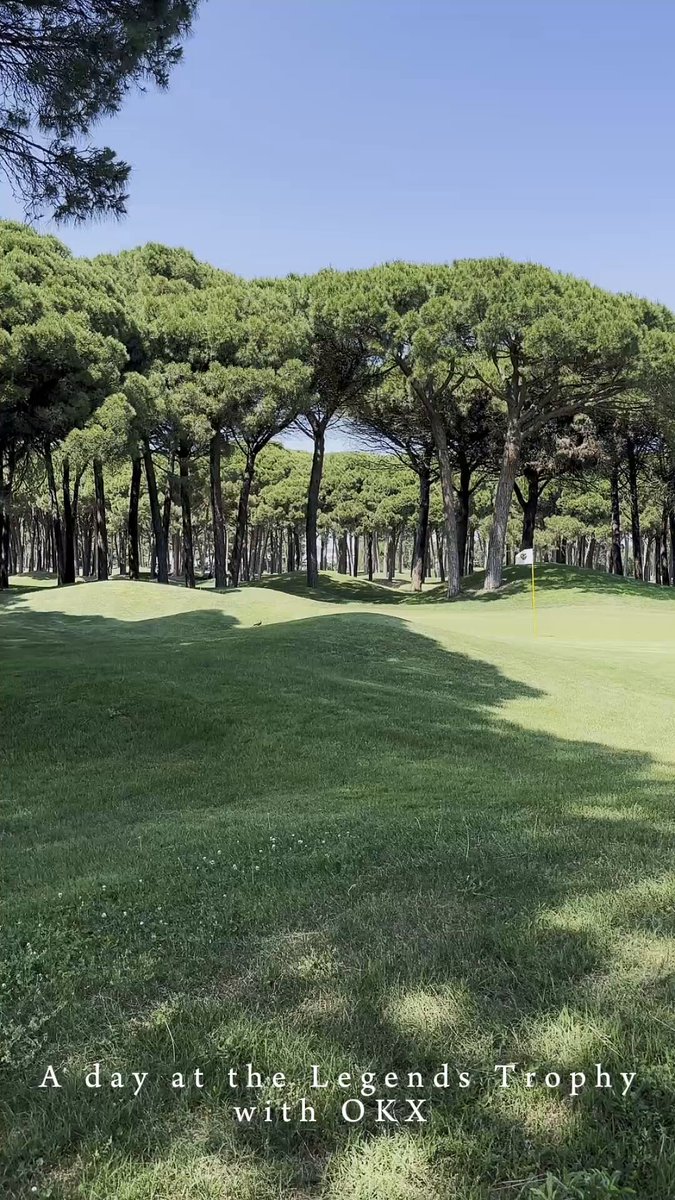 The image shows a lush green golf course with trees lining the fairways. The text "A day at the Legends Trophy" suggests that this scene takes place during July 1st. The image also includes a caption about exchanging money for golf, which implies that the location is a golf course or park where people can exchange their currency for golfing services.