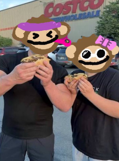 Two people standing outside a Costco Wholesale store eating food, with their faces covered by cartoon monkey stickers (one with a purple bandana, one with a pink bow).