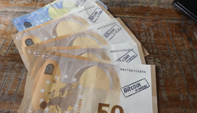 Several 50 Euro banknotes are fanned out on a wooden surface, each stamped with a label reading 'Bitcoin is better.'